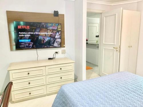 1 dormitorio con 1 cama y vestidor con TV en Ap Jardins c/ garagem CD 81, en São Paulo