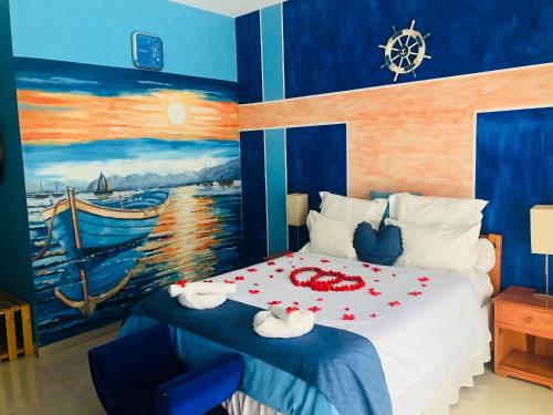 a bedroom with a bed with a painting on the wall at Petite Flower Guest House in Talata-maty