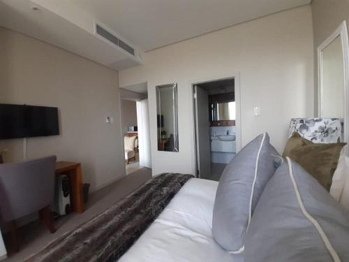 a bedroom with a white bed and a television at Zimbali Suite 606 in Ballito