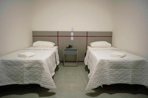 a room with two beds with white linens at Villa Vaz Hotel in Rondonópolis
