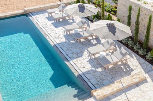 a group of chairs and umbrellas next to a swimming pool at Amani Living in Stoupa