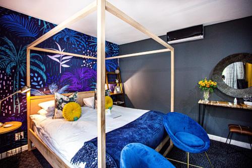 um quarto com uma cama de dossel e cadeiras azuis em Franschhoek Maison du Cap em Franschhoek