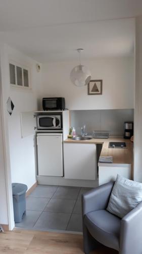 uma cozinha com armários brancos e um sofá num quarto em Studio "Normandise" em Le Tréport