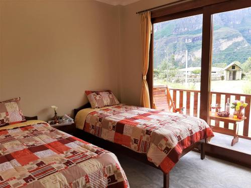 a bedroom with two beds and a balcony with a view at La Posada de Gocta in Cocachimba