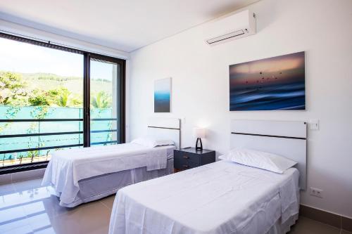 two beds in a room with a large window at Residencial Marina Del Sol in Pauba