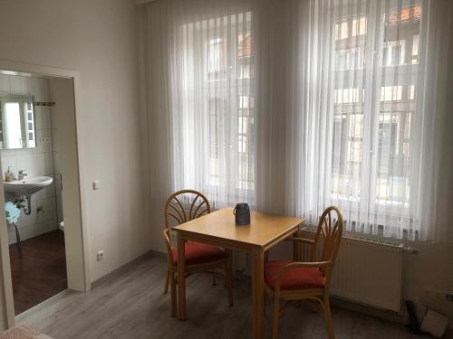 a table and chairs in a room with windows at Pension Hansehof in Salzwedel