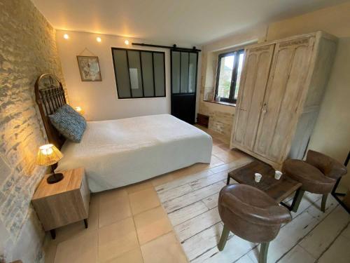 a bedroom with a bed and a desk and a chair at Le mas Normand in Ver-sur-Mer