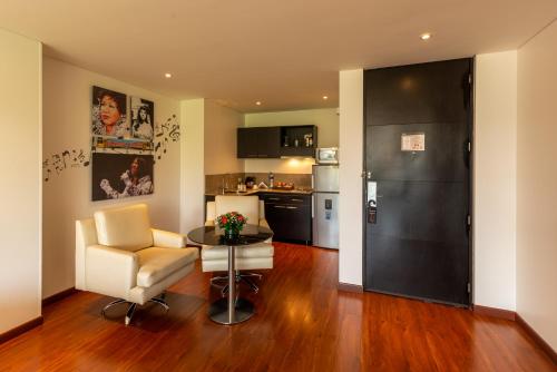 a living room with a table and a chair and a kitchen at Hotel Jazz Apartments in Bogotá