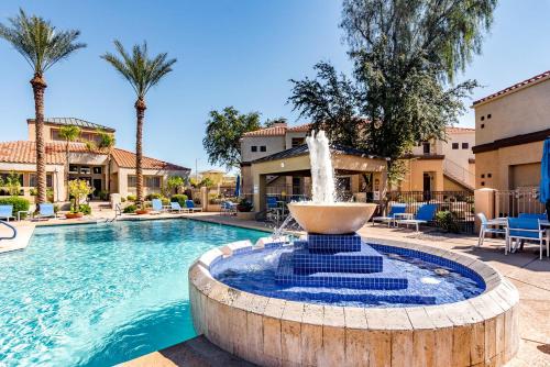 a fountain in the middle of a pool with palm trees at Sahuaro Condos in Scottsdale