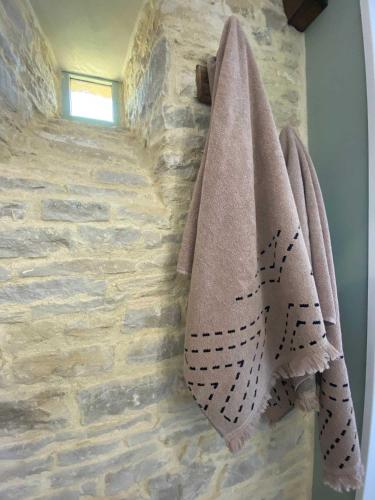 a bathroom with two towels hanging on a stone wall at Le mas Normand in Ver-sur-Mer