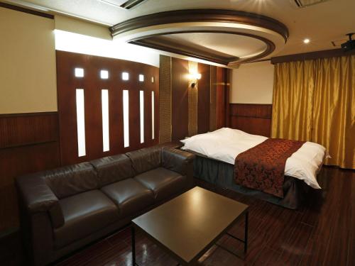 Hotel Fine Garden Gifu في Kakamigahara: غرفة في الفندق مع أريكة وسرير