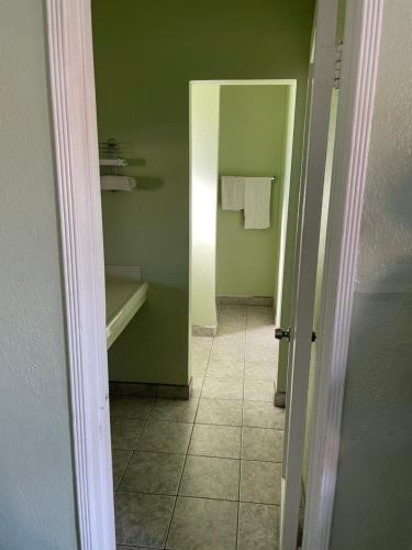 baño con paredes verdes y pasillo de azulejos en RAMONA MOTEL, en Hemet