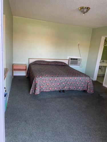 Un dormitorio con una cama con una manta. en RAMONA MOTEL, en Hemet