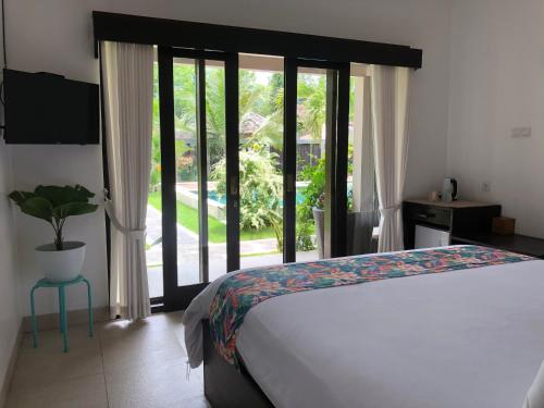 a bedroom with a bed and a large window at Kaien Villas Gili Air in Gili Air