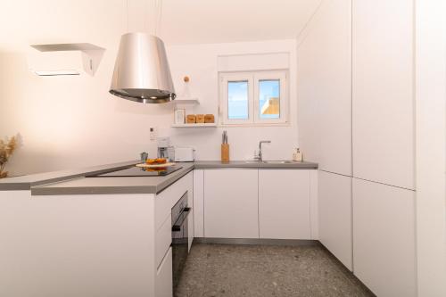 a white kitchen with white cabinets and a sink at Hygge Boutique Apartment in Trogir