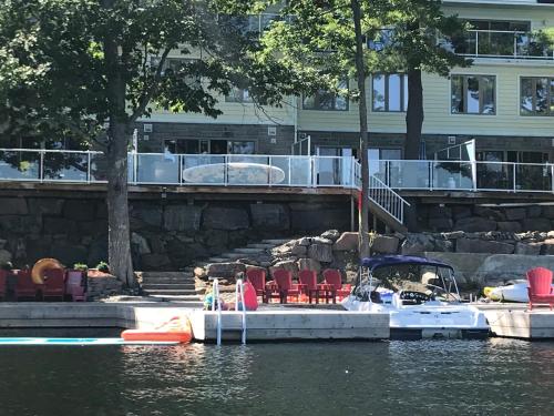 a dock with chairs and a boat in the water at Muskoka Lakes Hotel and Resorts in Port Carling