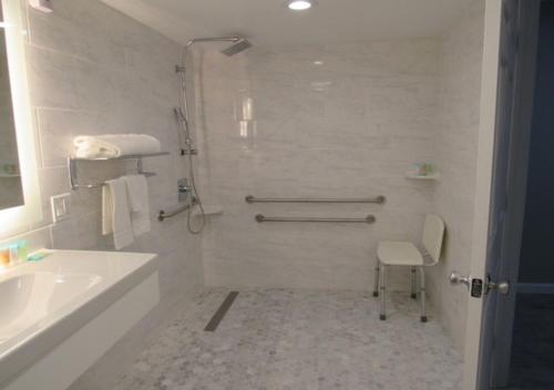 baño blanco con ducha y lavamanos en Capri Suites Anaheim en Anaheim