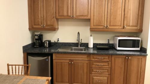 a kitchen with wooden cabinets and a sink and a microwave at Muskoka Lakes Hotel and Resorts in Port Carling