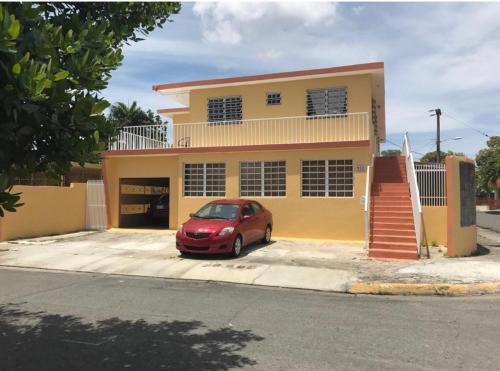 une voiture rouge garée devant une maison dans l'établissement San Juan Apartments, à San Juan