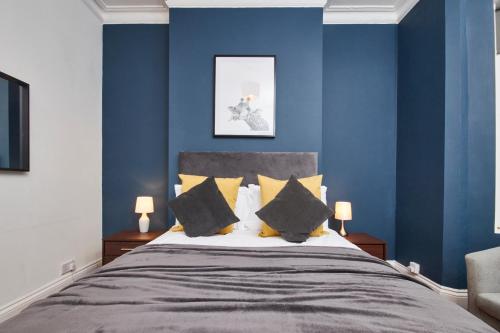 a bedroom with blue walls and a bed with yellow pillows at The Exquisite Leamington Spa House - Sleeps 8 in Leamington Spa