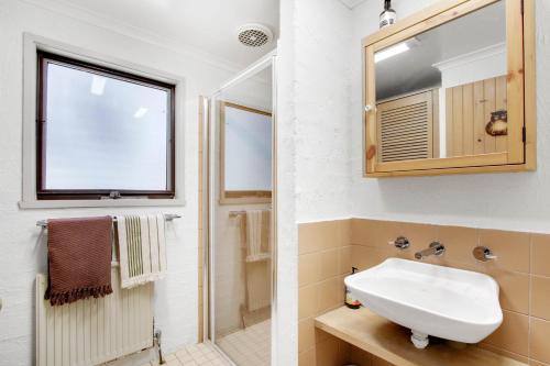 ein weißes Badezimmer mit einem Waschbecken und einem Spiegel in der Unterkunft Snowgums 09 in Dinner Plain