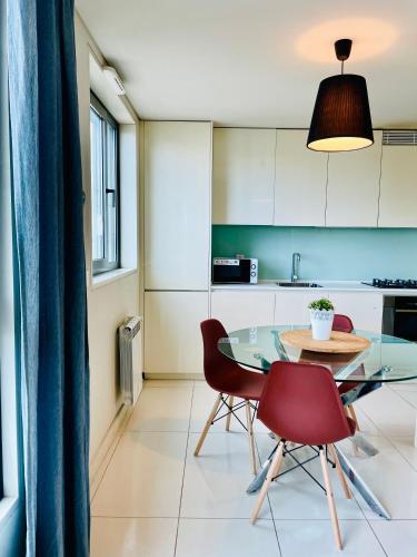 a kitchen with a glass table and two red chairs at ABC Expo Apartment in Lisbon