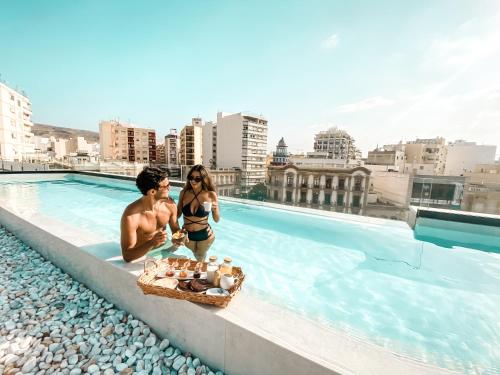 un hombre y una mujer en traje de baño sentados en una piscina en HO Puerta de Purchena, en Almería