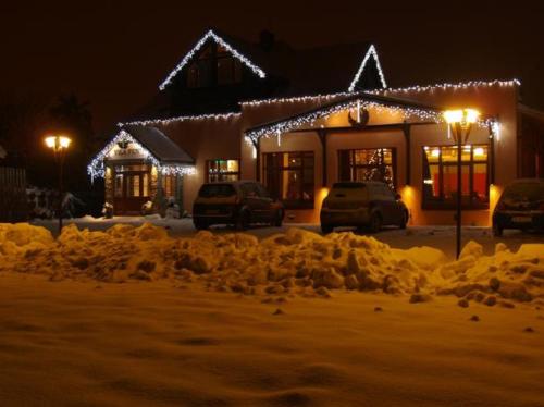 una casa cubierta de nieve por la noche con luces en Vila Fenix B&B, en Ružomberok