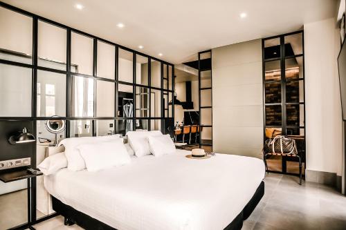 a large white bed in a room with glass walls at HO Puerta de Purchena By Olivencia in Almería