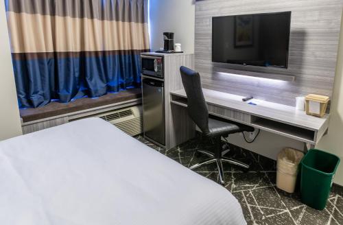 a room with a desk with a television and a bed at Microtel Inn & Suites by Wyndham Lloydminster in Lloydminster