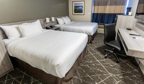 a hotel room with two beds and a desk at Microtel Inn & Suites by Wyndham Lloydminster in Lloydminster