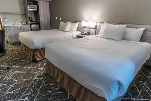 a hotel room with two beds and a chair at Microtel Inn & Suites by Wyndham Lloydminster in Lloydminster