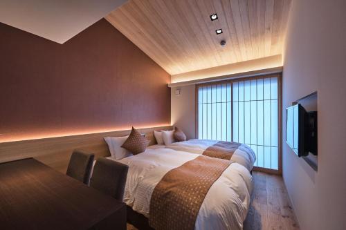 a bedroom with a bed and a tv and a table at Stay SAKURA Kyoto Gion Miyagawacho in Kyoto