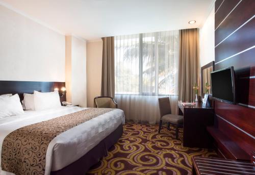 a hotel room with a bed and a television at Swiss-Belhotel Merauke in Merauke