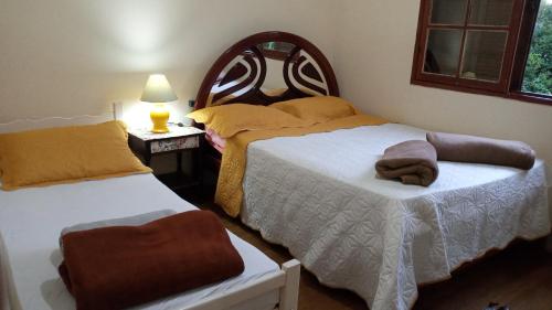 a bedroom with two beds and a table with a lamp at Hostel Café in Alto Caparao