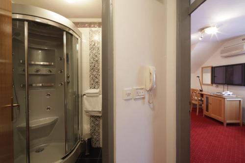 a bathroom with a shower and a phone on a wall at Hotel Millennium in Osijek