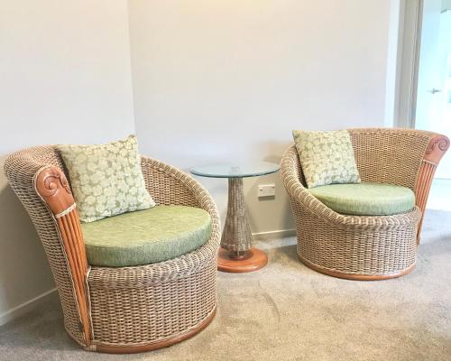 two wicker chairs and a table in a room at Road Sun Tourist Lodge in Dunedin