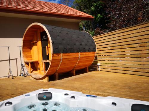 a circular wooden tub on a deck with a house at Road Sun Tourist Lodge in Dunedin