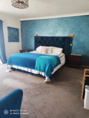 a bedroom with a bed with a blue wall at Private Room in Papamoa