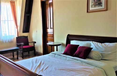 um quarto com uma cama, uma cadeira e uma janela em OBC Villa em Bandung