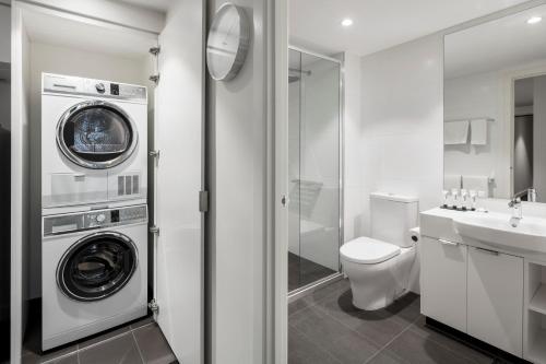 a bathroom with a washer and dryer next to a toilet at Quest St Kilda Road in Melbourne