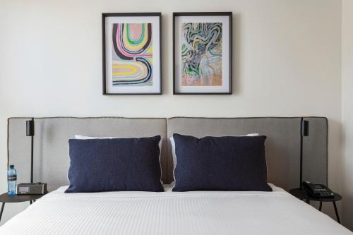 a bed with two framed paintings on the wall at Quest St Kilda Road in Melbourne