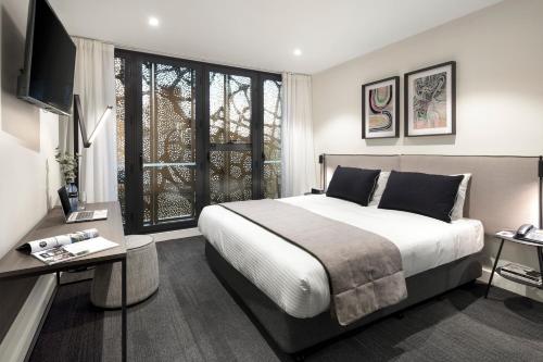 een slaapkamer met een groot bed en een televisie. bij Quest St Kilda Road in Melbourne