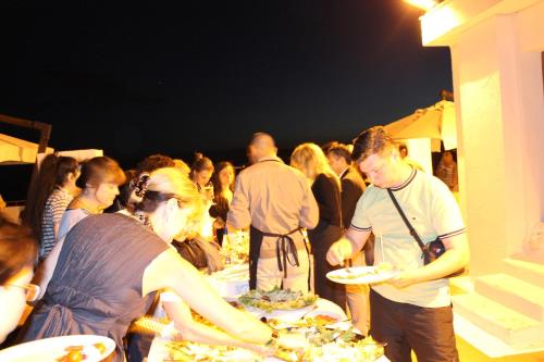 a group of people standing around a table with plates of food at Hotel Mediterraneo in Roccella Ionica