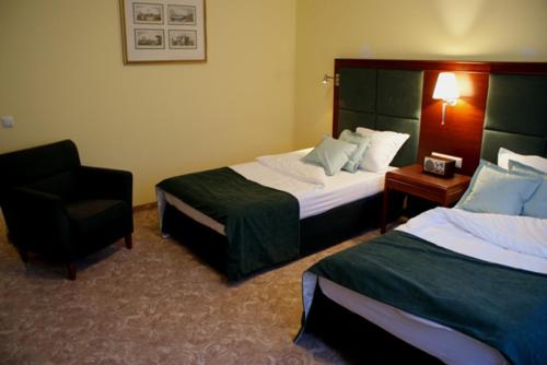 a hotel room with two beds and a chair at Hotel Wilga by Katowice Airport in Pyrzowice