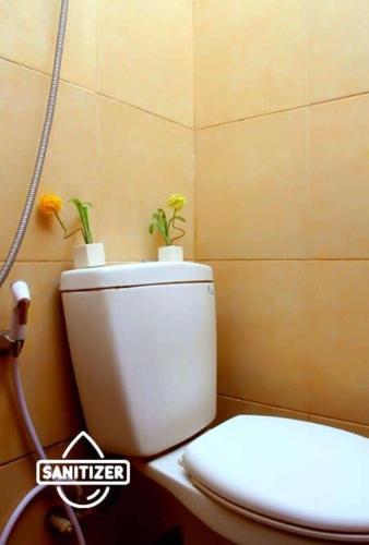 a bathroom with a toilet with two plants on it at Bantal Guling Trans in Bandung