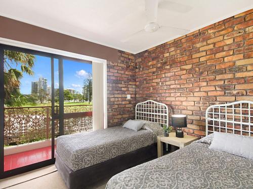 a bedroom with two beds and a brick wall at Coral Gardens Unit 2 in Coolangatta