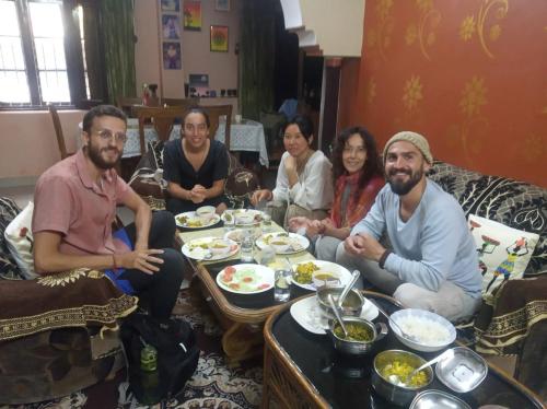 a group of people sitting around a table eating food at Gungun Homestay in Rishīkesh