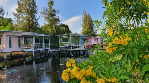 a row of houses on the water with yellow flowers at Phalagoon Resort in Ban Chang