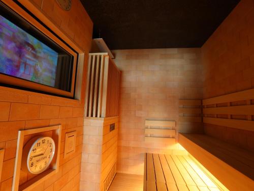 a sauna with a clock and a tv on the wall at Dormy Inn Ikebukuro - Natural Hot Spring in Tokyo
